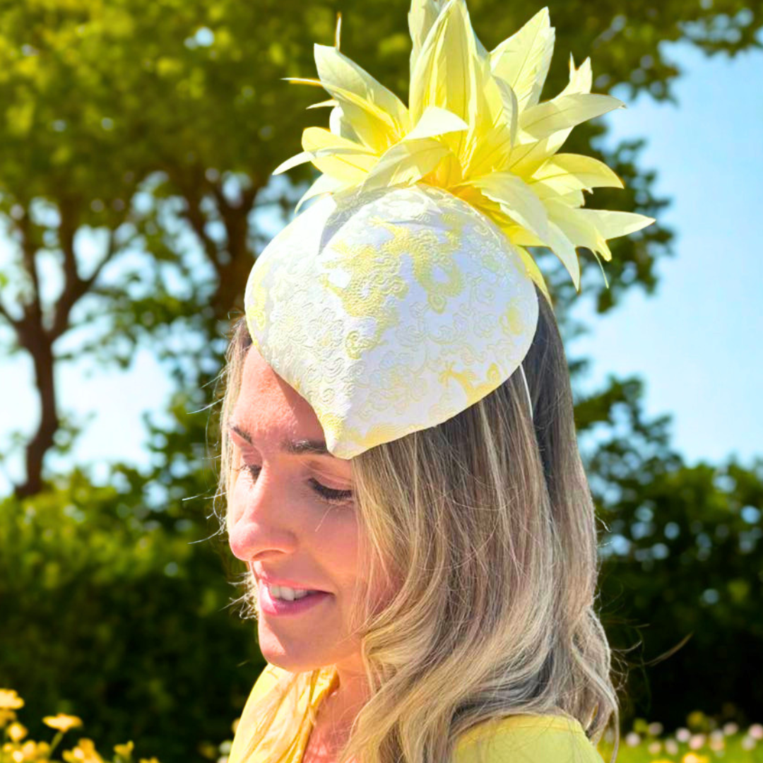 Woman wearing a yellow and white floral headpiece outdoors with greenery in the background